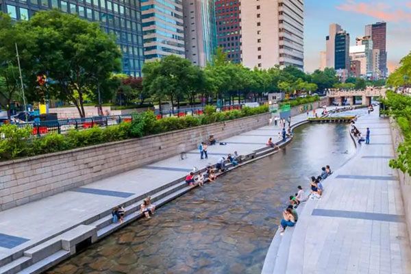 Suối Cheonggyecheon về đêm – lối đi dạo, cầu đá và ánh đèn phản chiếu trên mặt nước giữa lòng Seoul